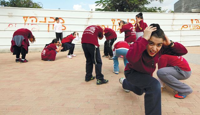 Children in Sderot role play a drill to take cover in a rocket attack.